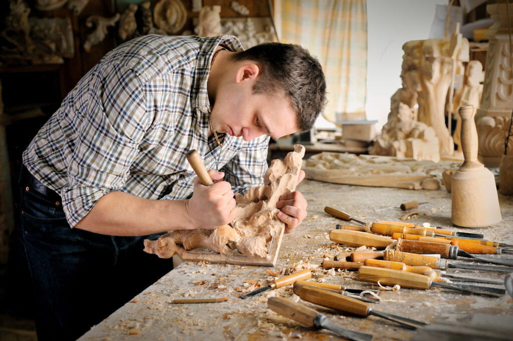 Young man carving wood in his man shed