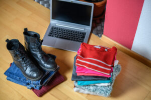 pile of second hand clothing and  shoes with computer on floor in living room
